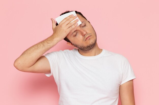 Une vue de face jeune homme en t-shirt blanc se frottant le front