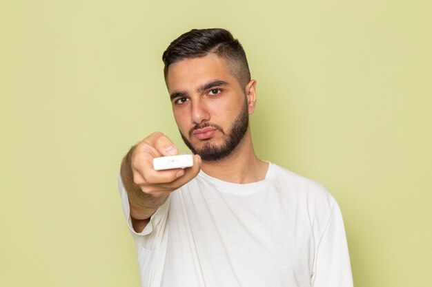 Une vue de face jeune homme en t-shirt blanc tenant la télécommande