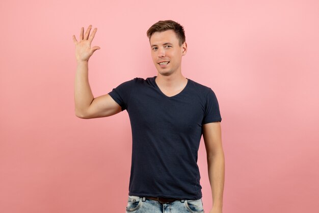 Vue de face jeune homme en t-shirt bleu montrant sa paume sur fond rose modèle de couleur de l'émotion humaine masculine