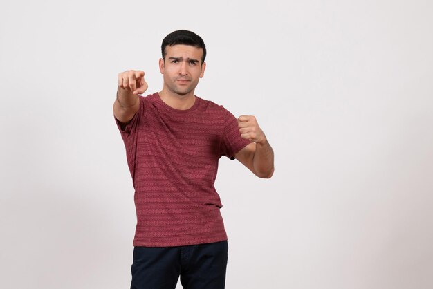 Vue de face jeune homme en t-shirt debout et posant sur fond blanc