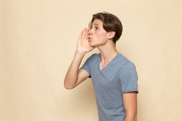 Une vue de face jeune homme en t-shirt gris appelant