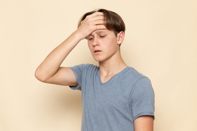 Une vue de face jeune homme en t-shirt gris ayant de graves maux de tête