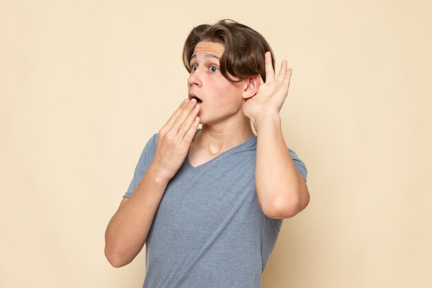 Une vue de face jeune homme en t-shirt gris essayant d'entendre