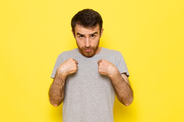 Une vue de face jeune homme en t-shirt gris avec expression confuse sur le mur jaune couleur émotion expression homme