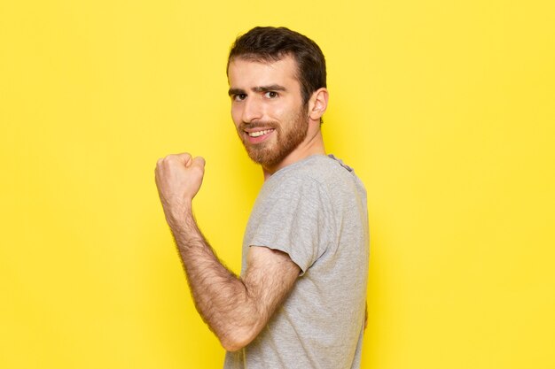 Une vue de face jeune homme en t-shirt gris avec une expression ravie sur le mur jaune homme couleur modèle vêtements émotion