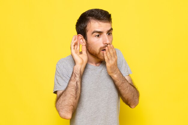 Une vue de face jeune homme en t-shirt gris avec une expression de surprise sur le mur jaune homme couleur modèle émotion vêtements