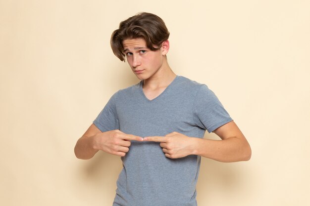 Une vue de face jeune homme en t-shirt gris posant avec les doigts