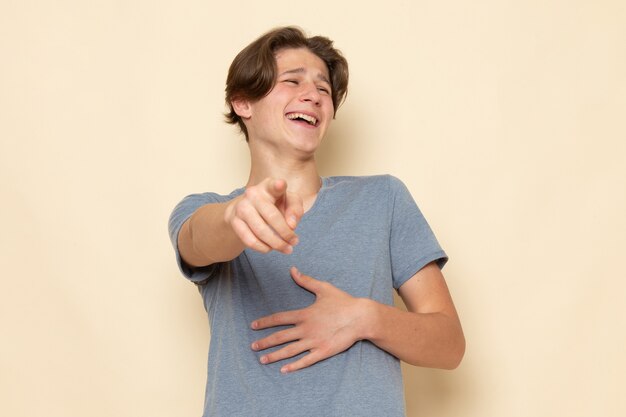 Une vue de face jeune homme en t-shirt gris posant en riant