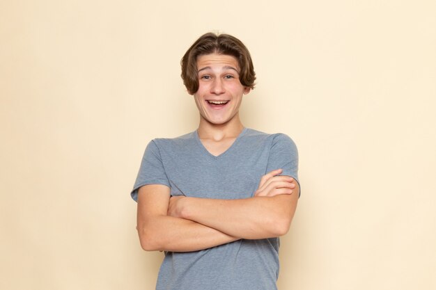 Une vue de face jeune homme en t-shirt gris posant avec rire