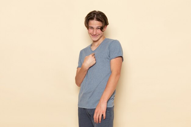 Une vue de face jeune homme en t-shirt gris posant avec sourire