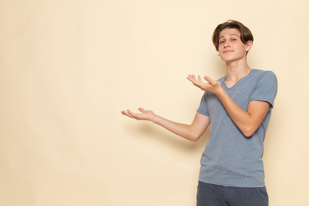 Une vue de face jeune homme en t-shirt gris posant avec sourire