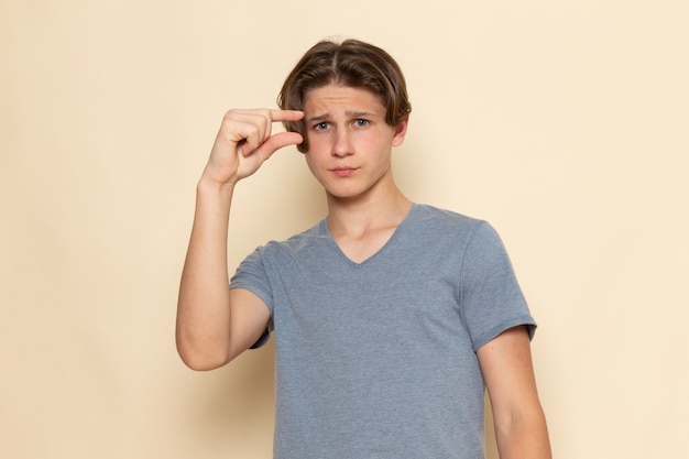 Une vue de face jeune homme en t-shirt gris posant