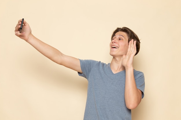 Une vue de face jeune homme en t-shirt gris prenant un selfie