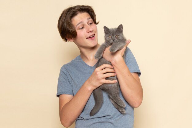 Une vue de face jeune homme en t-shirt gris tenant mignon chaton gris