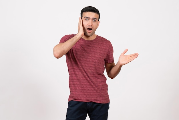 Vue de face jeune homme en t-shirt posant sur fond blanc