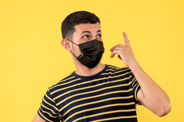 Vue de face jeune homme en t-shirt rayé noir et blanc debout sur fond jaune