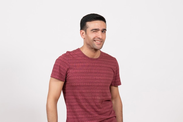 Vue de face jeune homme en t-shirt rouge foncé clignotant sur fond blanc