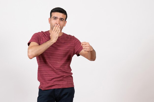 Vue de face jeune homme en t-shirt rouge foncé debout sur fond blanc