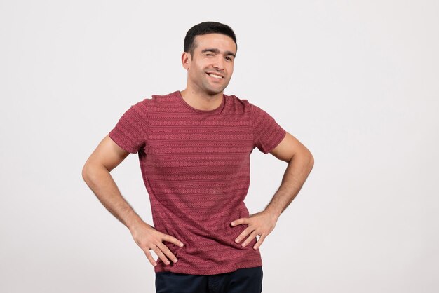 Vue de face jeune homme en t-shirt rouge foncé debout sur fond blanc