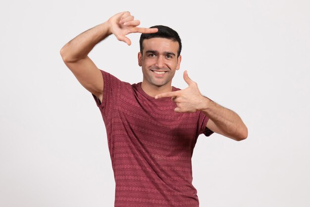 Vue de face jeune homme en t-shirt rouge foncé debout sur fond blanc