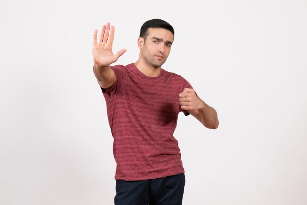 Vue de face jeune homme en t-shirt rouge foncé debout sur fond blanc