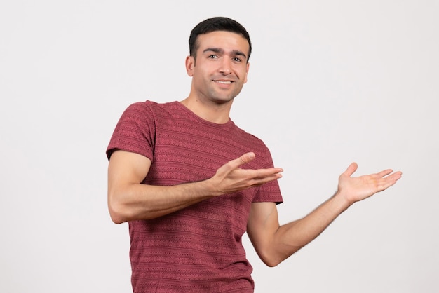 Vue de face jeune homme en t-shirt rouge foncé debout sur fond blanc