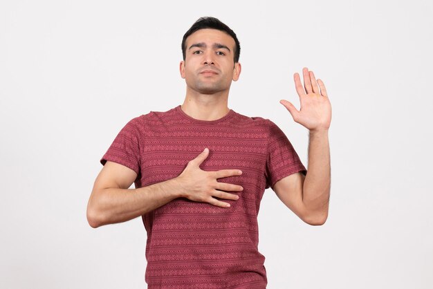 Vue de face jeune homme en t-shirt rouge foncé debout sur fond blanc