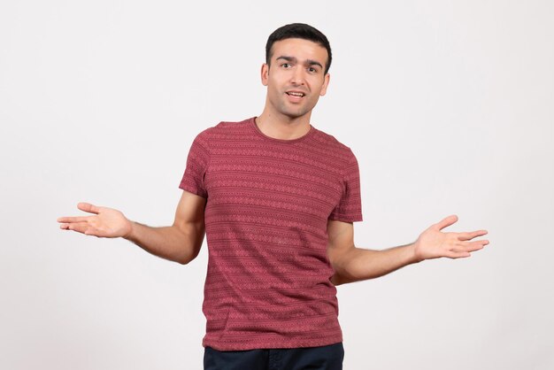 Vue de face jeune homme en t-shirt rouge foncé debout sur fond blanc