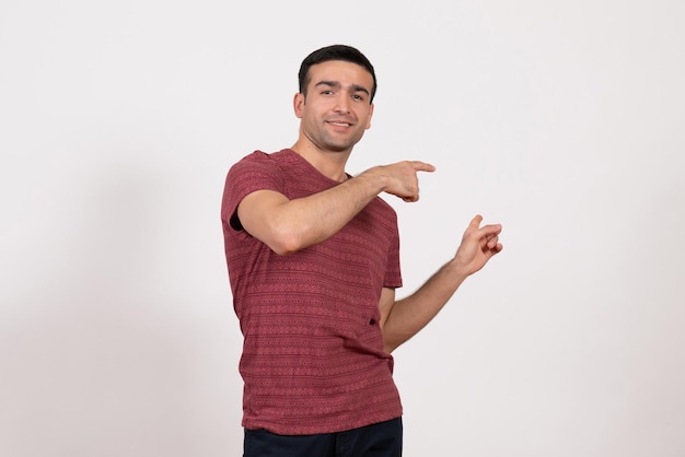 Vue de face jeune homme en t-shirt rouge foncé posant sur fond blanc