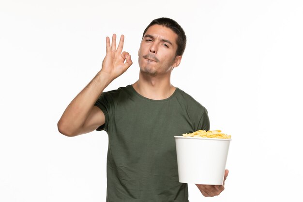 Vue de face jeune homme en t-shirt vert tenant panier avec pommes de terre cips sur mur blanc lonely plaisir film cinéma cinéma