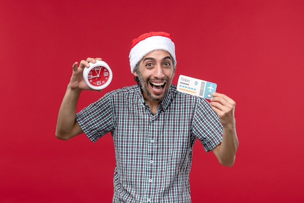 Vue de face jeune homme tenant un billet avec horloge sur fond rouge