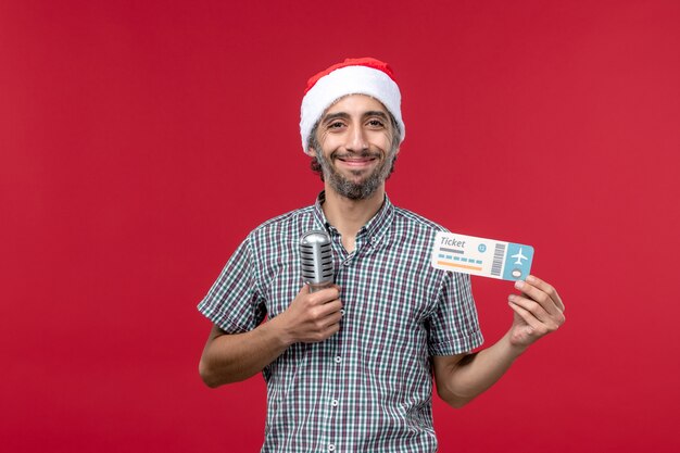 Vue de face jeune homme tenant un billet avec micro sur fond rouge