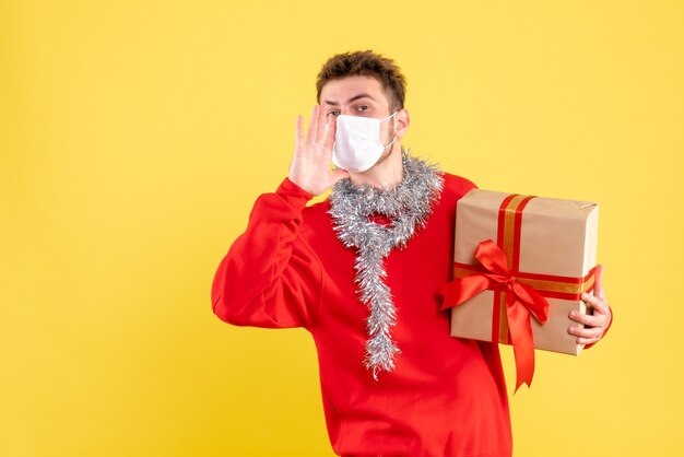 Vue de face jeune homme tenant un cadeau de Noël dans un masque stérile