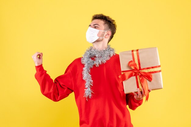Vue de face jeune homme tenant un cadeau de Noël dans un masque stérile