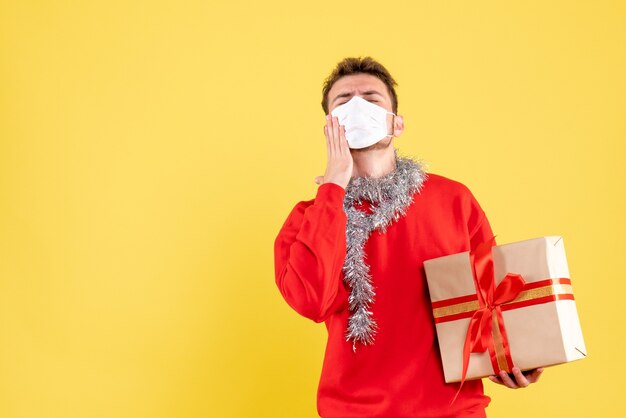 Vue de face jeune homme tenant un cadeau de Noël dans un masque stérile