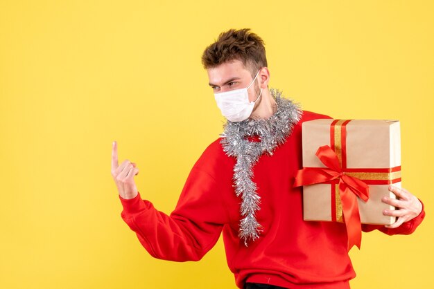 Vue de face jeune homme tenant un cadeau de Noël dans un masque stérile