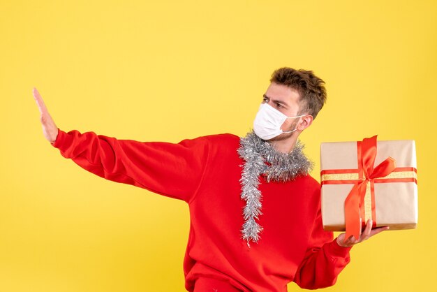 Vue de face jeune homme tenant un cadeau de Noël dans un masque stérile