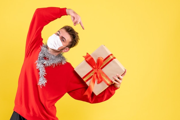 Vue de face jeune homme tenant le cadeau de Noël