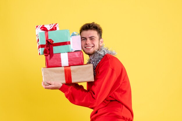 Vue de face jeune homme tenant des cadeaux de Noël