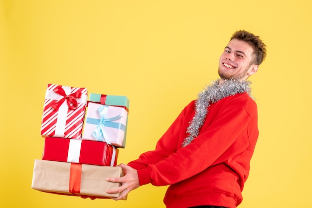 Vue de face jeune homme tenant des cadeaux de Noël