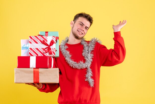 Vue de face jeune homme tenant des cadeaux de Noël