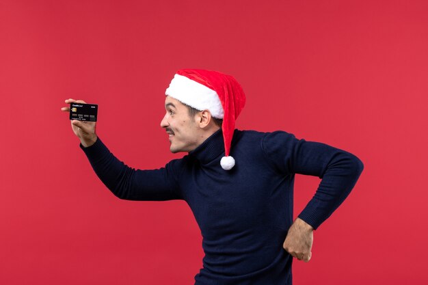 Vue de face jeune homme tenant une carte bancaire noire sur fond rouge