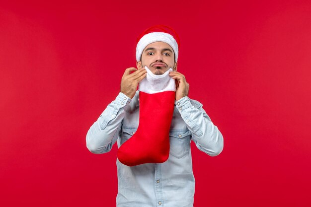 Vue de face jeune homme tenant la chaussette de Noël, Noël de vacances
