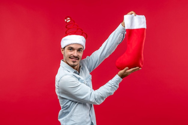 Vue de face jeune homme tenant la chaussette de Noël, Noël de vacances