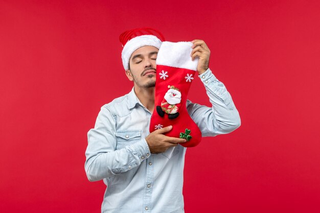 Vue de face jeune homme tenant la chaussette de Noël, Noël de vacances