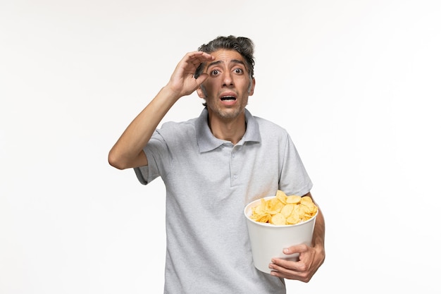 Vue De Face Jeune Homme Tenant Des Croustilles Sur Une Surface Blanche