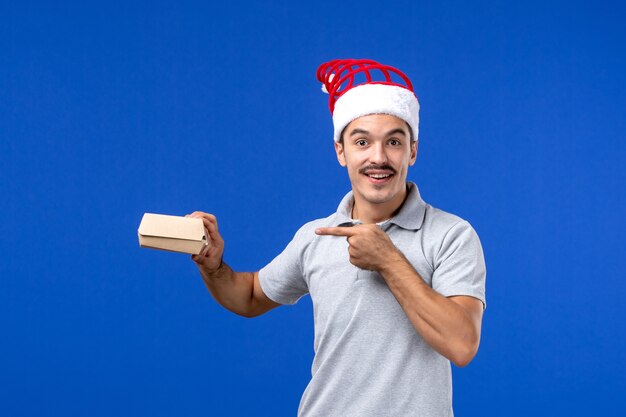 Vue de face jeune homme tenant un paquet de nourriture sur le mur bleu emploi de service masculin alimentaire