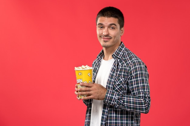 Vue de face jeune homme tenant le paquet de pop-corn sur la surface rouge des films de cinéma cinéma théâtre