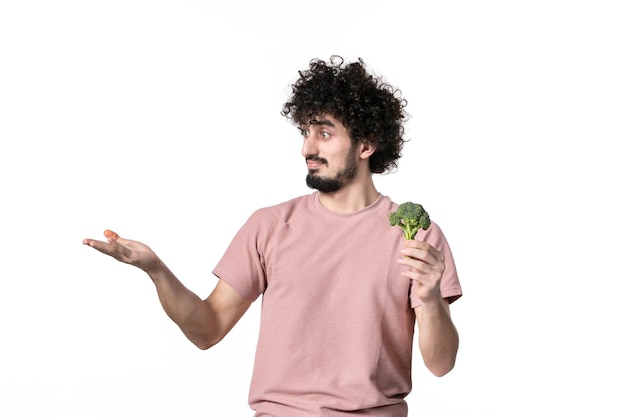 Vue de face jeune homme tenant peu de brocoli vert sur fond blanc corps légume horizontal régime alimentaire santé poids salade