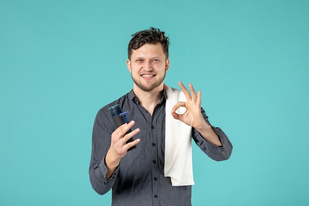 Vue de face jeune homme tenant un rasoir sur fond bleu